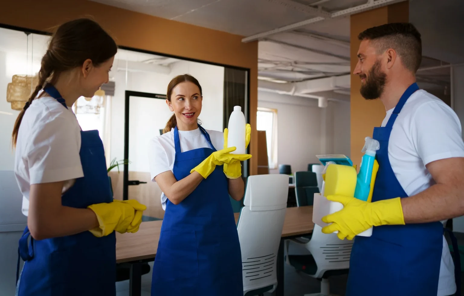 Professional cleaning staff in aprons and yellow gloves discussing cleaning products and services.